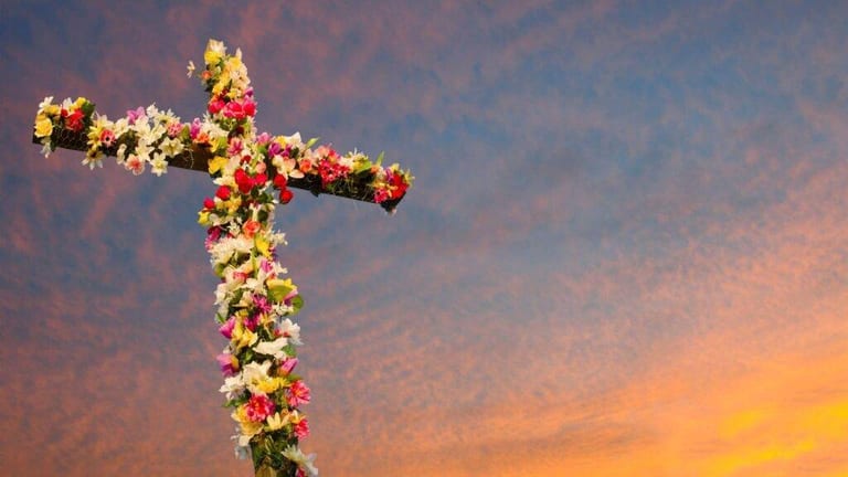 Congregation gathered outdoors at dawn for an Easter sunrise service as light breaks over the horizon