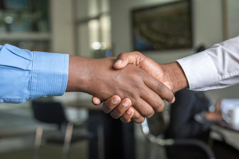 Two people shaking hands across a table in an office