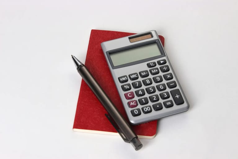 Calculator and pen resting on a red notebook