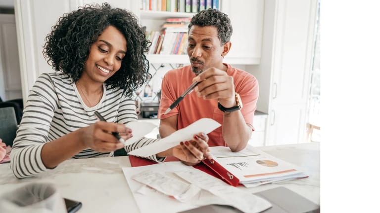 Couple reviewing household bills and receipts at a kitchen table