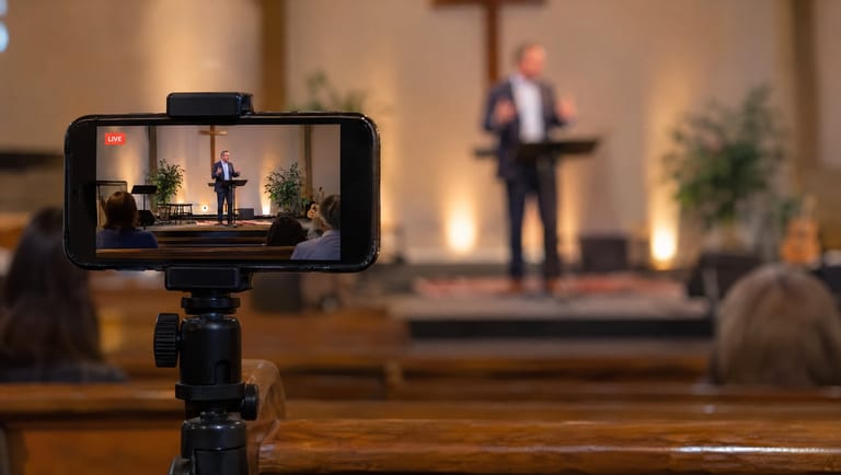A smartphone on a tripod livestreaming a small church service